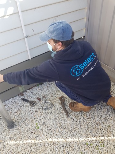 Plumber with mask working on outside drains Moonee Ponds